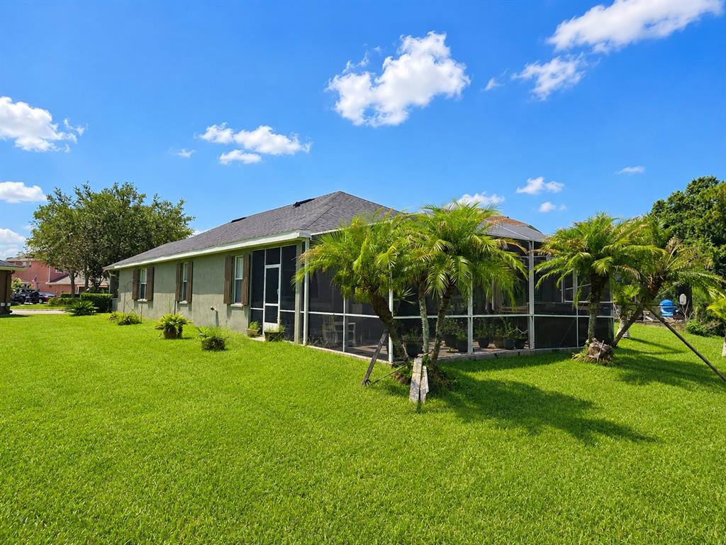 A house with a screened-in patio and palm trees sits on a grassy lawn — 9305 MANDRAKE COURT, TAMPA, FL
