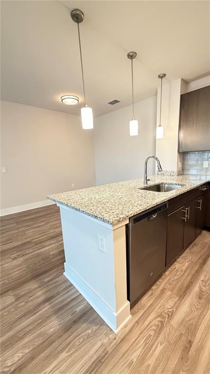 A kitchen island with a granite countertop, stainless steel sink, and dishwasher sits on wood-look flooring — 530 ACADEMY DRIVE UNIT 201, KISSIMMEE, FL