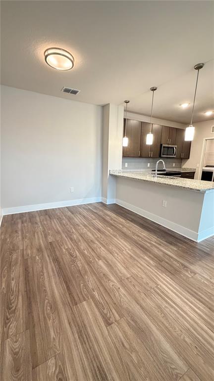 An open kitchen with granite countertops and wood-look flooring flows into an adjacent dining area — 530 ACADEMY DRIVE UNIT 201, KISSIMMEE, FL
