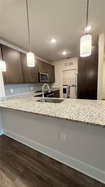A kitchen features dark wood cabinets, granite countertops, a stainless steel sink, and pendant lighting — 530 ACADEMY DRIVE UNIT 201, KISSIMMEE, FL