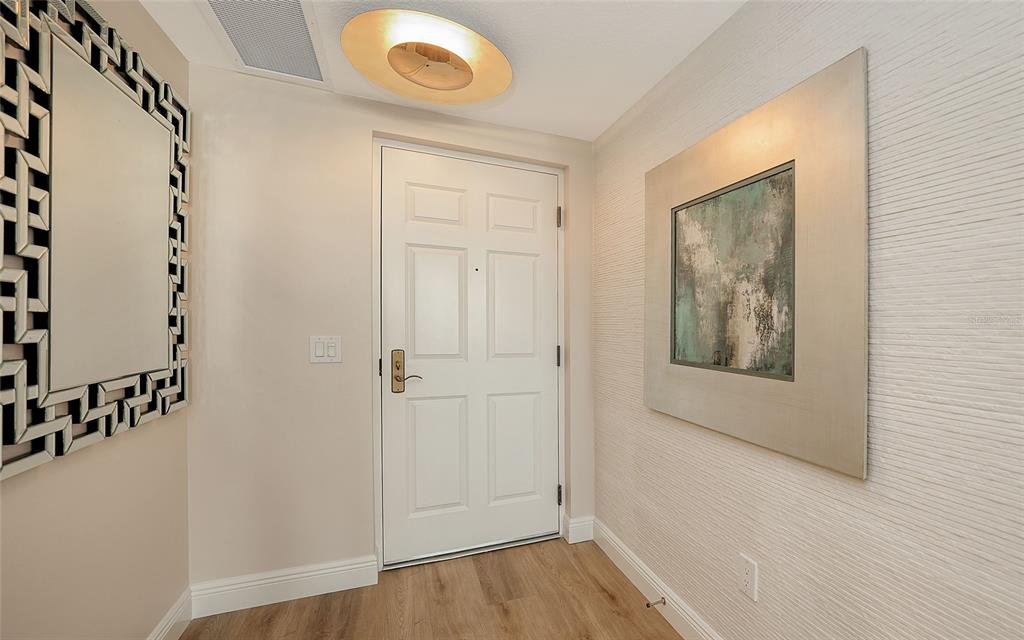 An entryway features a white door, a large decorative mirror, and textured wallpaper — 800 N TAMIAMI TRAIL UNIT 312, SARASOTA, FL