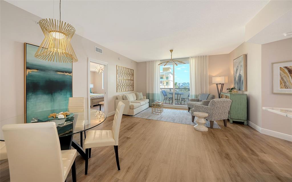A bright living and dining area with light wood floors, modern furniture, and balcony access — 800 N TAMIAMI TRAIL UNIT 312, SARASOTA, FL