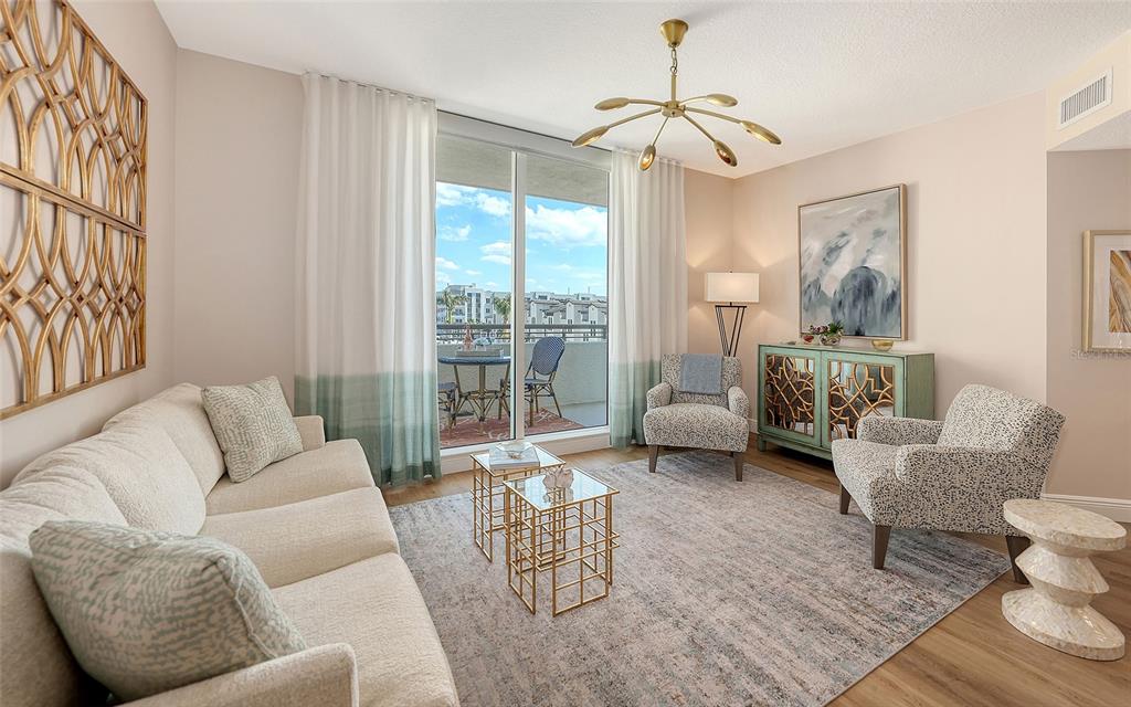 A living room with a beige sofa, two patterned armchairs, and a gold chandelier — 800 N TAMIAMI TRAIL UNIT 312, SARASOTA, FL