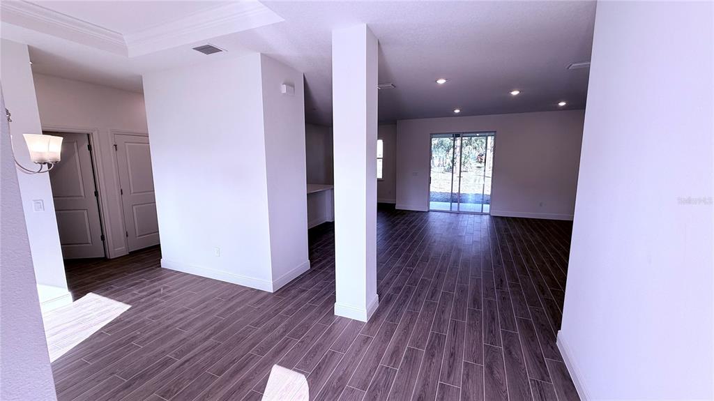 An open-concept living area features wood-look tile flooring, white walls, and a sliding glass door — 32 WESTRIDGE LANE, PALM COAST, FL