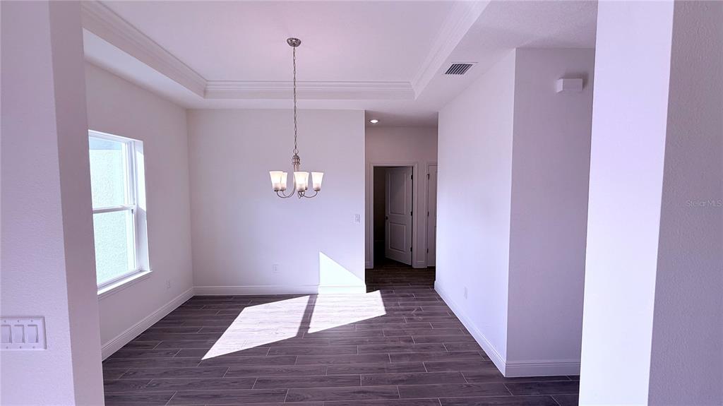 A dining area features a tray ceiling, a chandelier, and dark wood-look tile flooring — 32 WESTRIDGE LANE, PALM COAST, FL