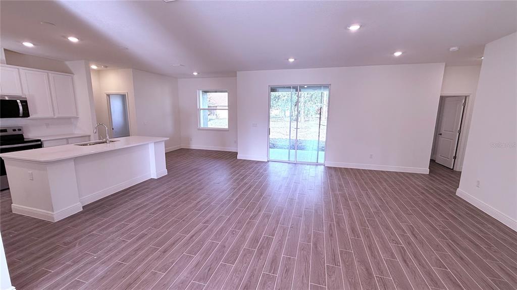 An open-concept kitchen and living area features white cabinetry, a kitchen island, and wood-look flooring — 32 WESTRIDGE LANE, PALM COAST, FL