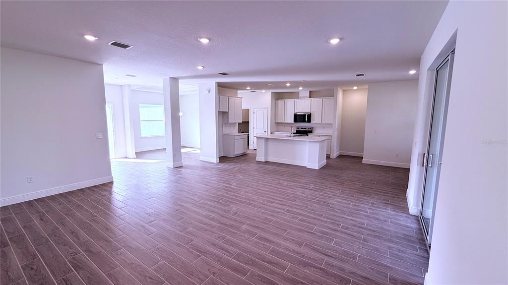 An open-concept kitchen and living area feature white cabinetry, a center island, and wood-look flooring — 32 WESTRIDGE LANE, PALM COAST, FL