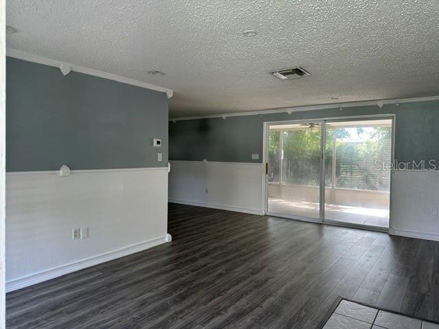 A living area features gray walls, white wainscoting, dark wood-look flooring, and a sliding glass door — 10840 NORWOOD AVENUE, PORT RICHEY, FL