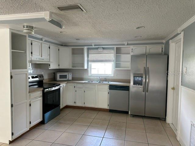 A kitchen features white cabinetry, stainless steel appliances, tiled floors, and a window above the sink — 10840 NORWOOD AVENUE, PORT RICHEY, FL