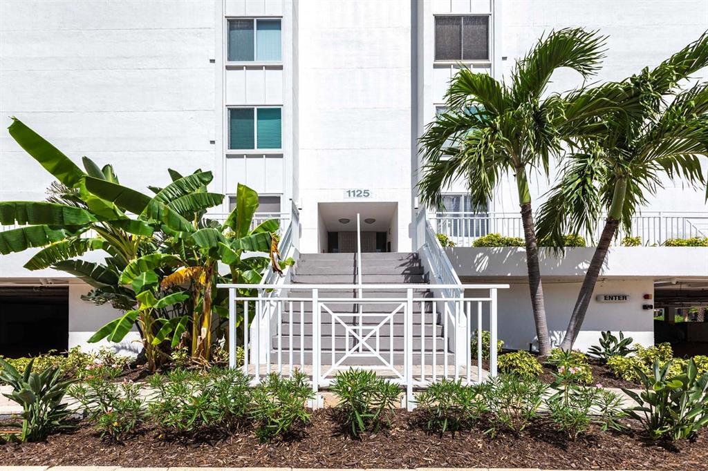 The exterior of a white multi-story building features a central staircase leading to an entrance — 1125 W PEPPERTREE DRIVE UNIT 707, SARASOTA, FL