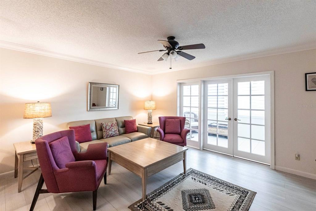 A living room features a sofa, two purple armchairs, a coffee table, and glass doors — 1125 W PEPPERTREE DRIVE UNIT 707, SARASOTA, FL