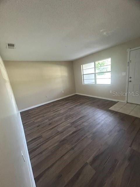 An empty living room features wood-look flooring, beige walls, and a window near the door — 222 ALBERT STREET, WINTER SPRINGS, FL