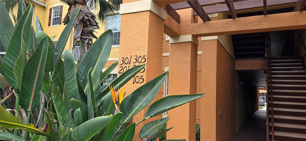 An exterior view of an apartment building entrance with stairs and unit numbers on pillars — 6240 CONTESSA DRIVE UNIT 103, ORLANDO, FL