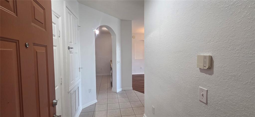 An entryway with tile flooring leads to an arched hallway and a living area — 6240 CONTESSA DRIVE UNIT 103, ORLANDO, FL