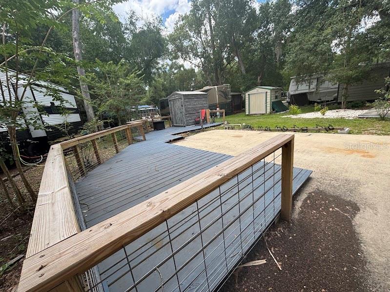 A wooden deck with wire railings leads toward a small shed and nearby RVs — 25219 141ST LANE NE UNIT 252, FORT MC COY, FL