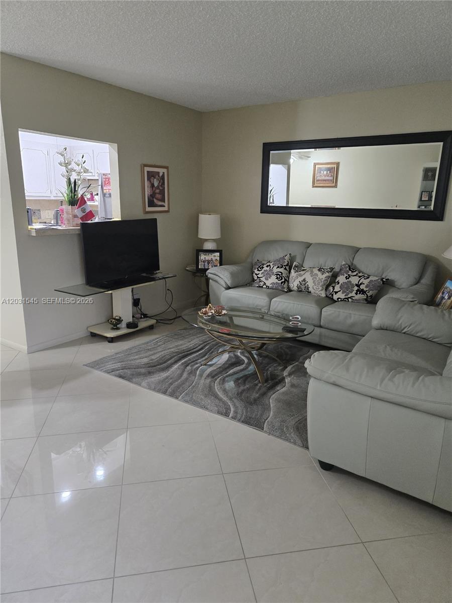 A living room features light-colored tile floors, a gray sofa, and a glass coffee table — DEERFIELD BEACH, FL