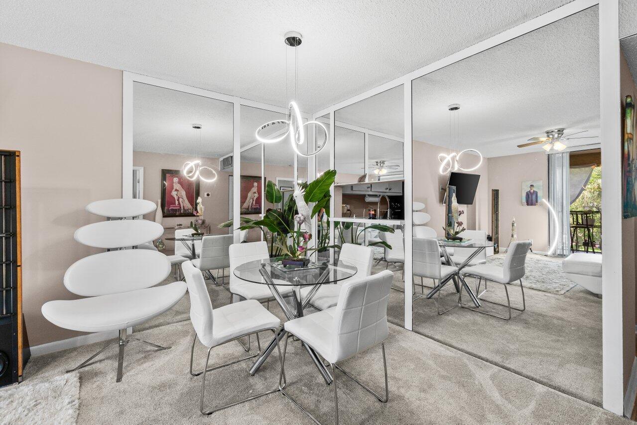 A dining area features a glass table, white chairs, and a large mirrored accent wall — 5100 Las Verdes Circle # 316, Delray Beach FL 33484, DELRAY BEACH, FL