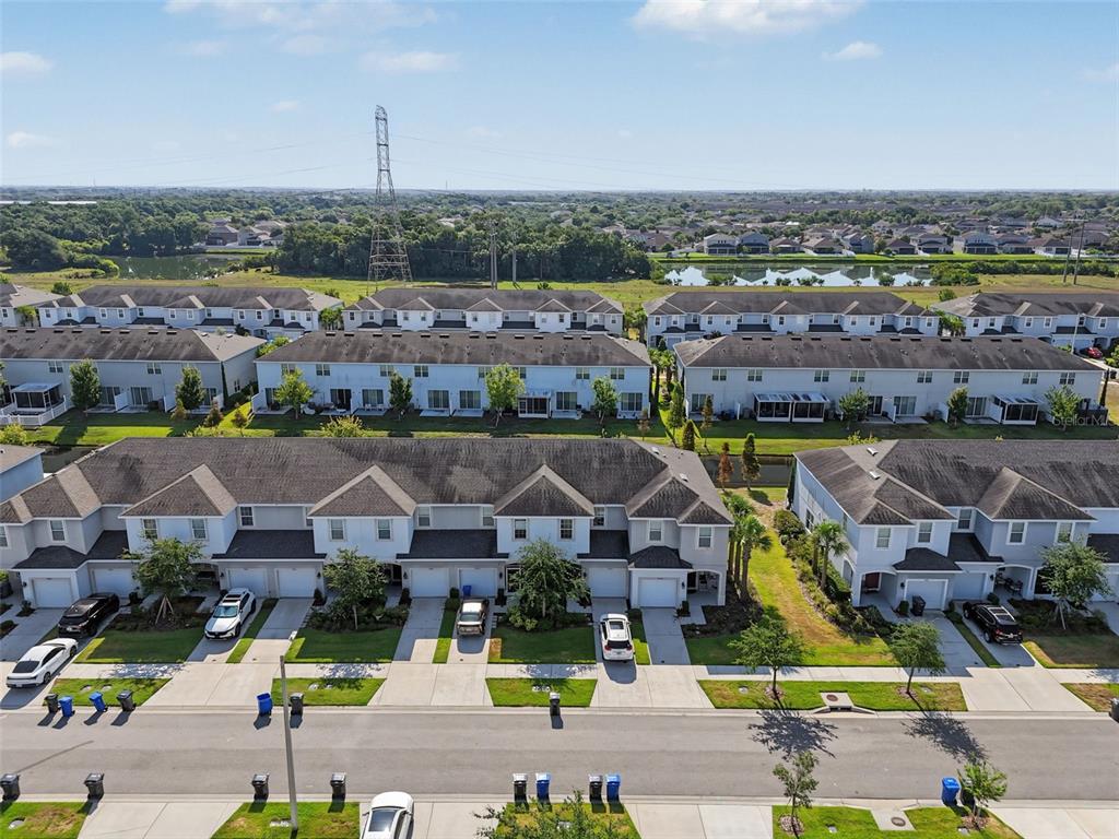 An aerial view shows rows of suburban townhouses with driveways and a nearby pond — 7052 SUMMER HOLLY PLACE, RIVERVIEW, FL
