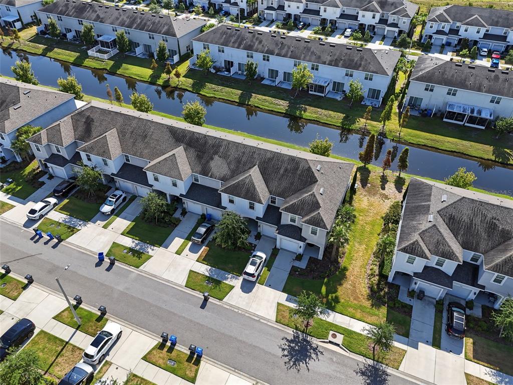 An aerial view shows a row of townhouses with a canal in the background — 7052 SUMMER HOLLY PLACE, RIVERVIEW, FL