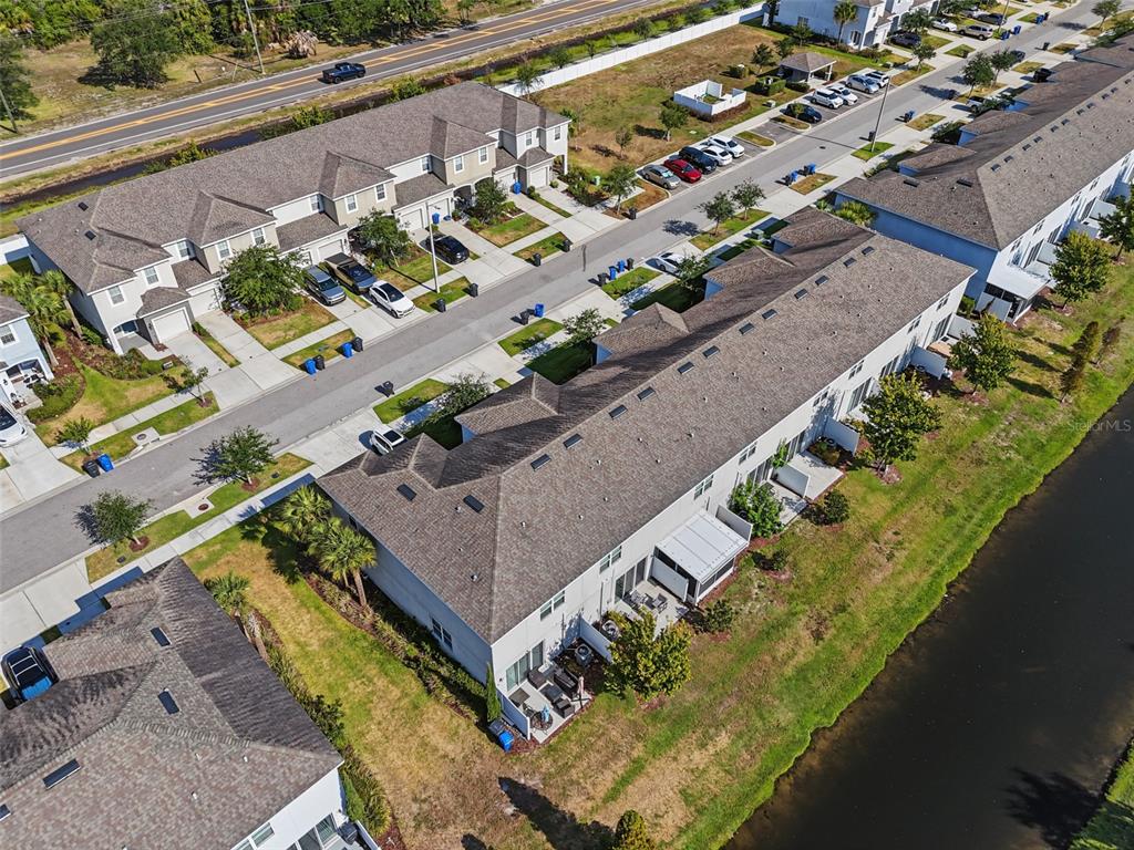 An aerial view shows a row of townhouses with attached garages next to a canal — 7052 SUMMER HOLLY PLACE, RIVERVIEW, FL