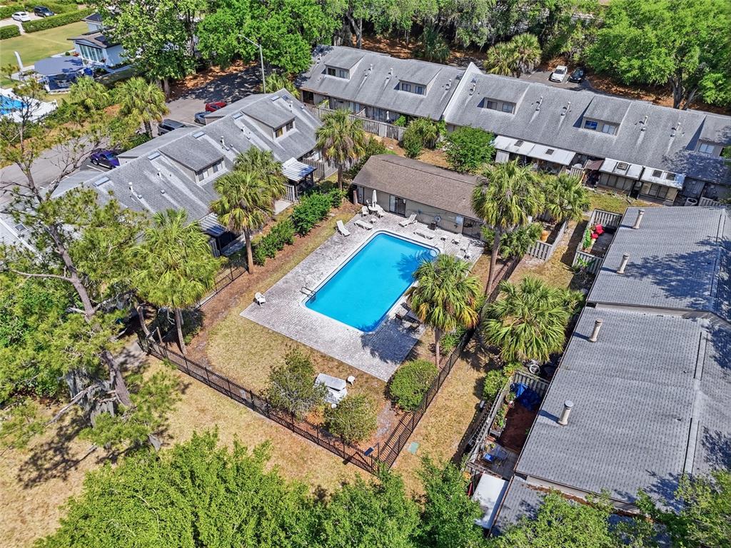 An aerial view shows a rectangular swimming pool surrounded by a patio and palm trees — 3426 NW 37TH AVENUE UNIT 3426, GAINESVILLE, FL