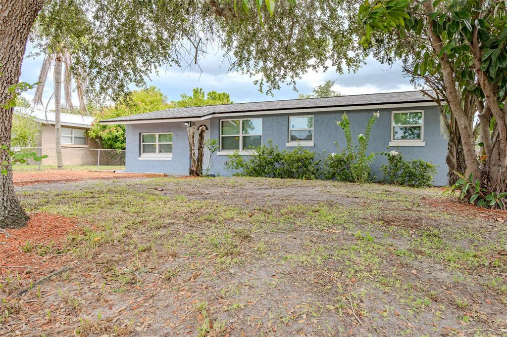 A single-story blue house with a gray roof sits on a grassy, tree-shaded lot — 217 BETTY AVENUE S, DUNDEE, FL