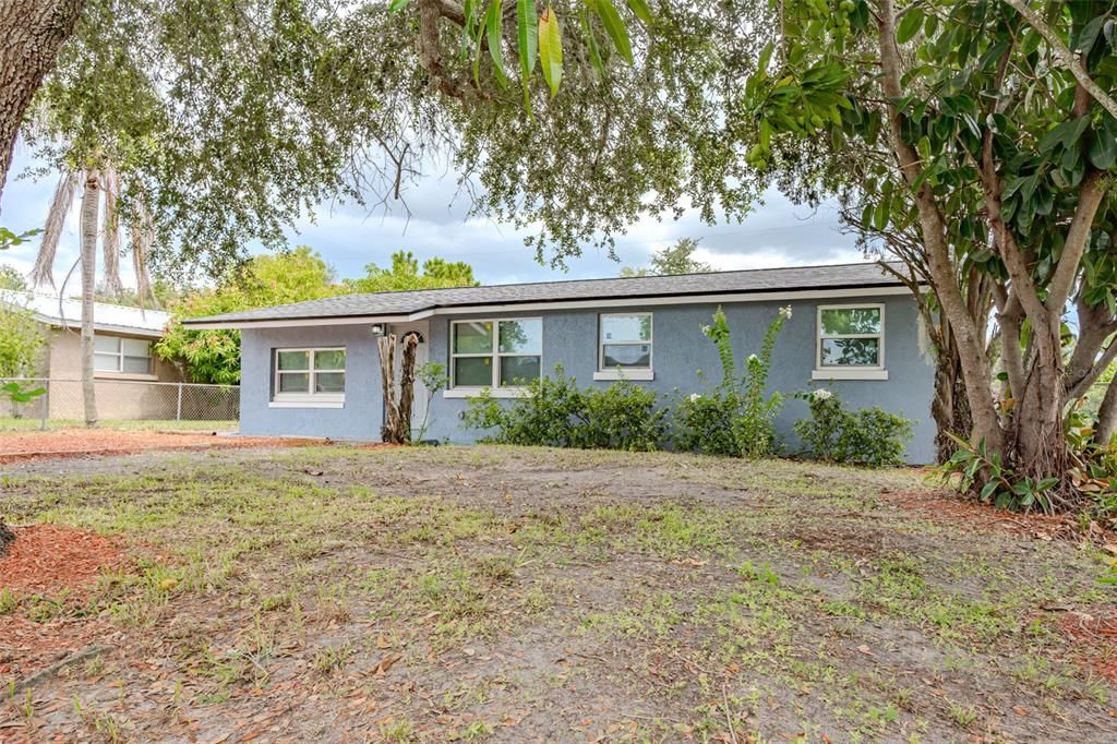 A single-story blue house with a low-pitched roof sits on a grassy lot with trees — 217 BETTY AVENUE S, DUNDEE, FL