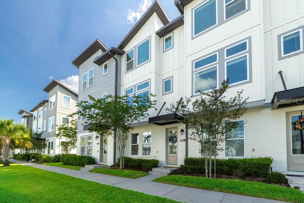 A row of modern three-story townhomes with white brick and gray siding exteriors — 12941 GABOR AVENUE, ORLANDO, FL