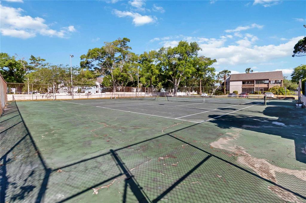 An outdoor tennis court with a chain-link fence and surrounding trees under a blue sky — 440 ORIENTA POINT STREET, ALTAMONTE SPRINGS, FL
