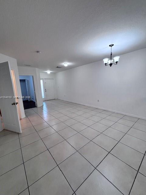 An empty room features white walls, light-colored tile flooring, and a hanging chandelier — 13726 SW 171st Ln, Miami FL 33177, MIAMI, FL