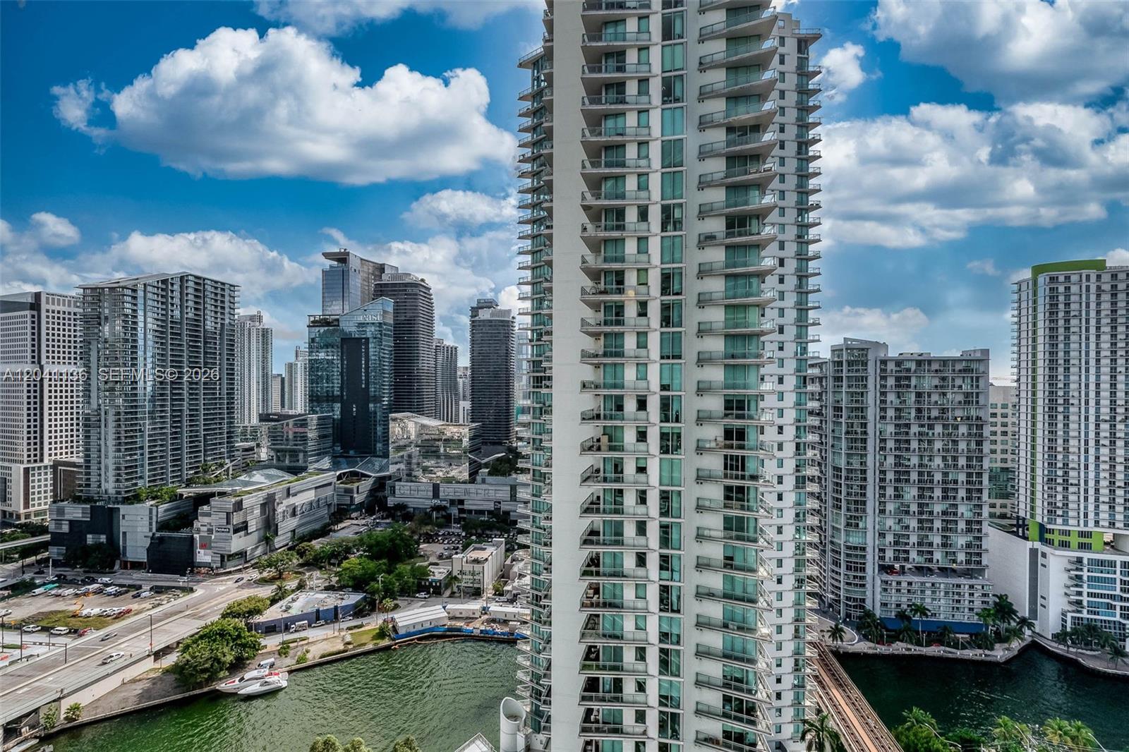 An aerial view of a tall residential skyscraper overlooking a river and city skyline — 90 SW 3rd St # 3211, Miami FL 33130, MIAMI, FL