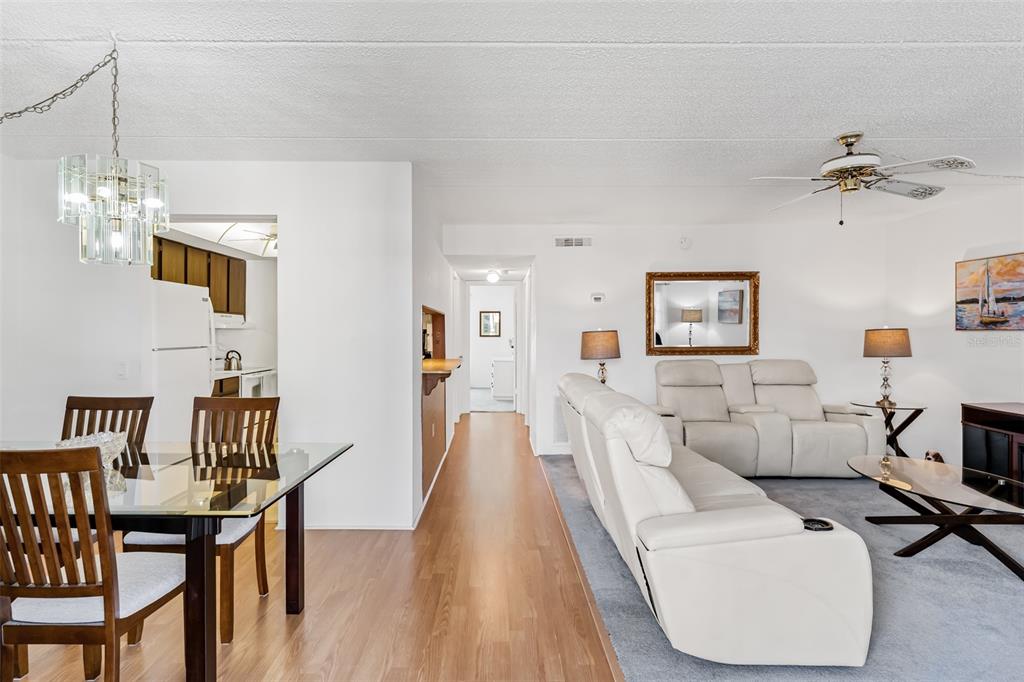 A living room and dining area feature wood-look flooring, white walls, and a white sofa — 12760 INDIAN ROCKS ROAD UNIT 546, LARGO, FL