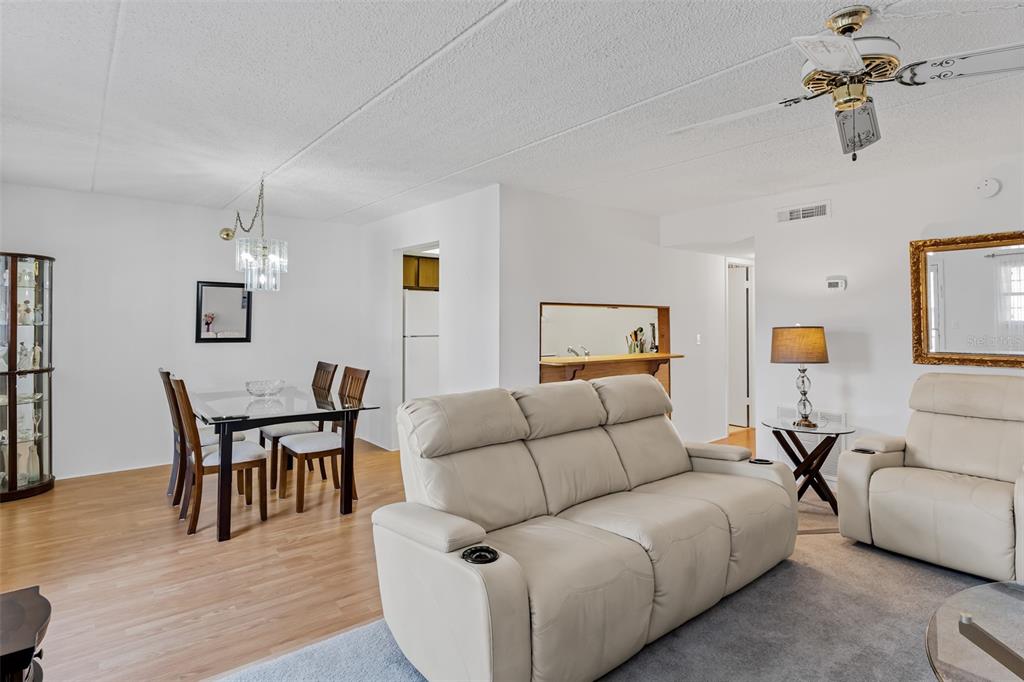 A living room and dining area with white walls, light wood flooring, and neutral furniture — 12760 INDIAN ROCKS ROAD UNIT 546, LARGO, FL