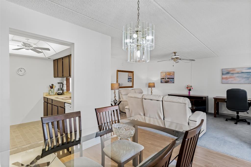 A dining area with a glass table and chandelier overlooks a living room and kitchen — 12760 INDIAN ROCKS ROAD UNIT 546, LARGO, FL
