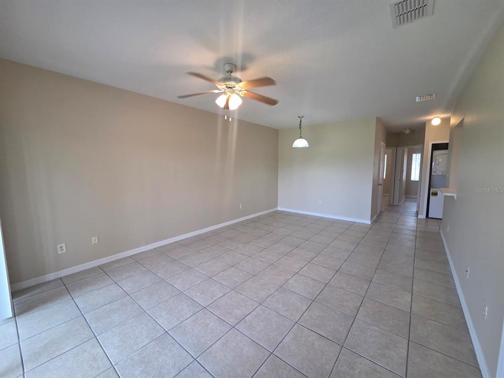 An empty room with beige walls, tile flooring, a ceiling fan, and a pendant light — 489 LAS CORTES LANE UNIT 204, ORLANDO, FL