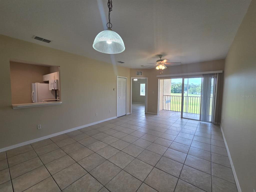 An open living area with tile floors, a ceiling fan, and a sliding glass door — 489 LAS CORTES LANE UNIT 204, ORLANDO, FL