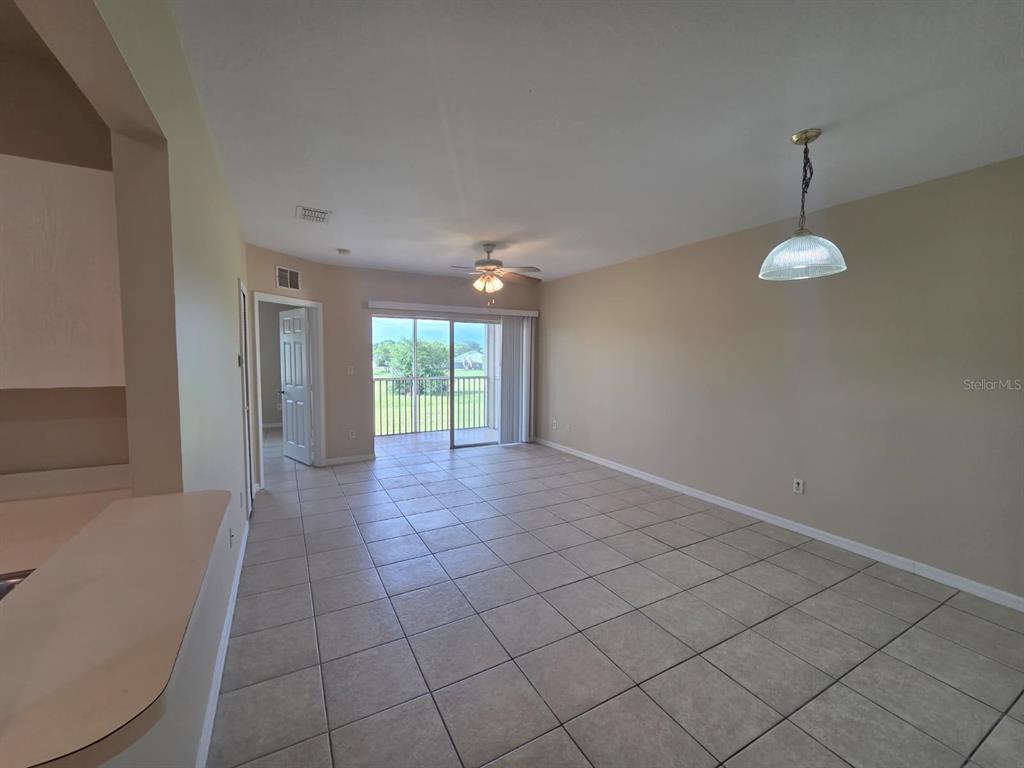 An open-concept living and dining area features beige tile flooring and a sliding glass door — 489 LAS CORTES LANE UNIT 204, ORLANDO, FL