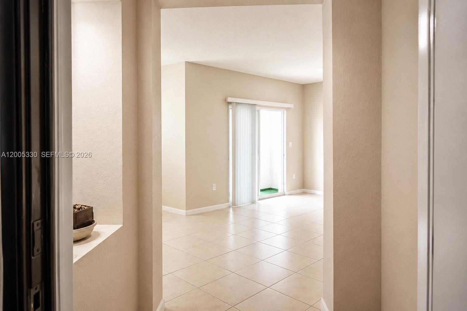 A view through a doorway into a tiled living area with a sliding glass door — 11503 NW 89th St # 213, Doral FL 33178, DORAL, FL