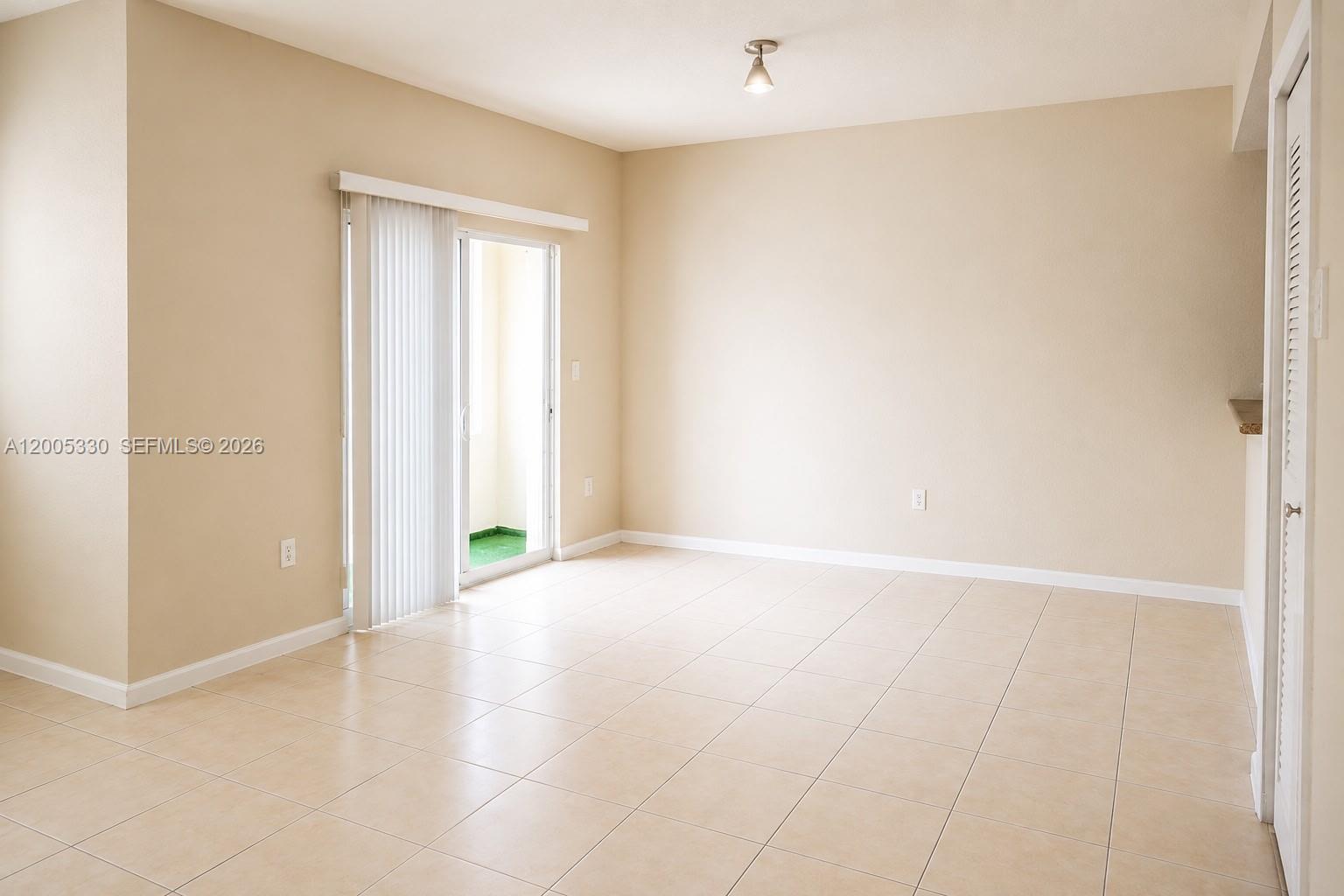 An empty room features beige walls, light-colored tile flooring, and a sliding glass door — 11503 NW 89th St # 213, Doral FL 33178, DORAL, FL