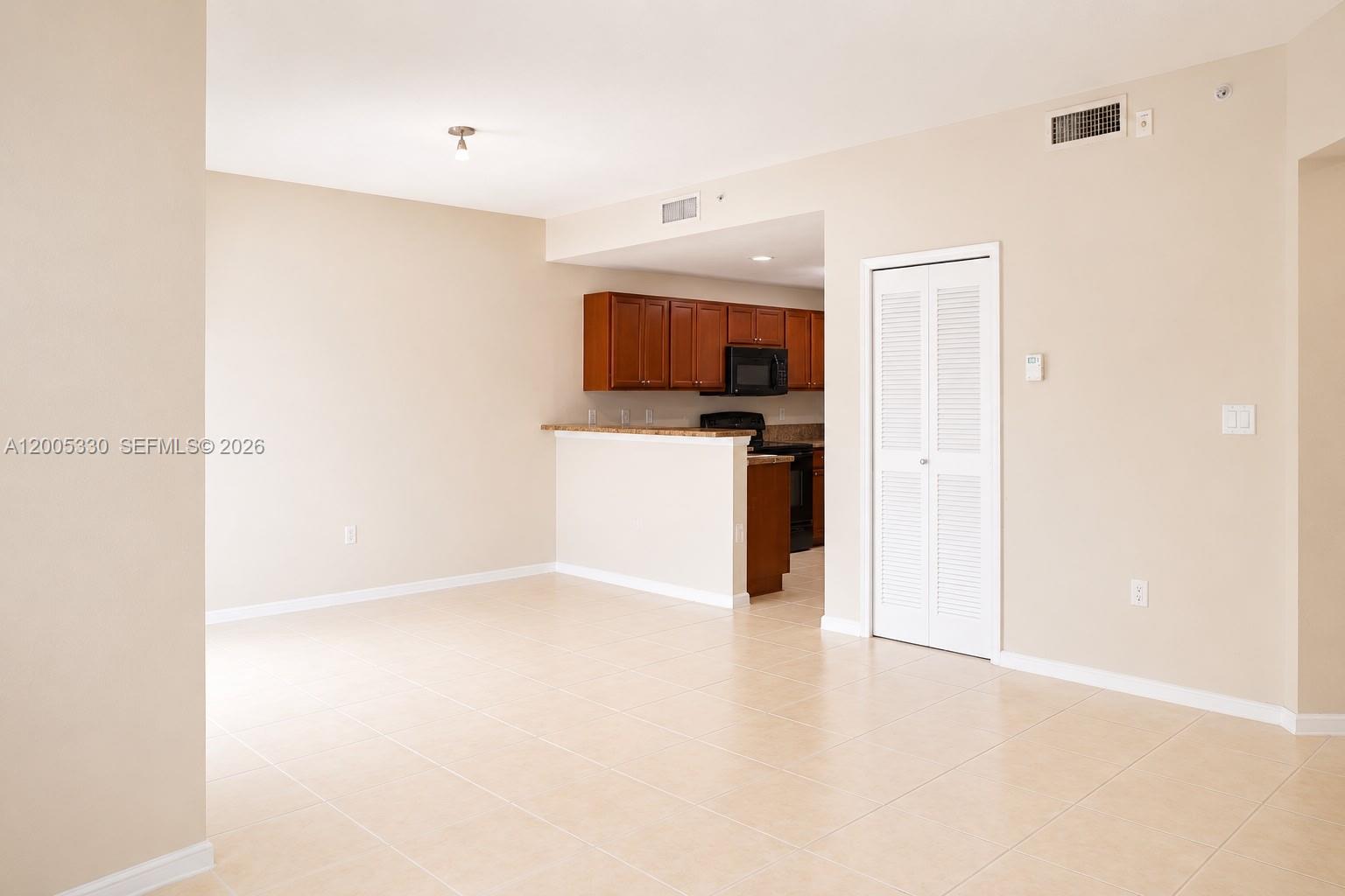 An open-concept living area features beige tile flooring, neutral walls, and a pass-through kitchen — 11503 NW 89th St # 213, Doral FL 33178, DORAL, FL