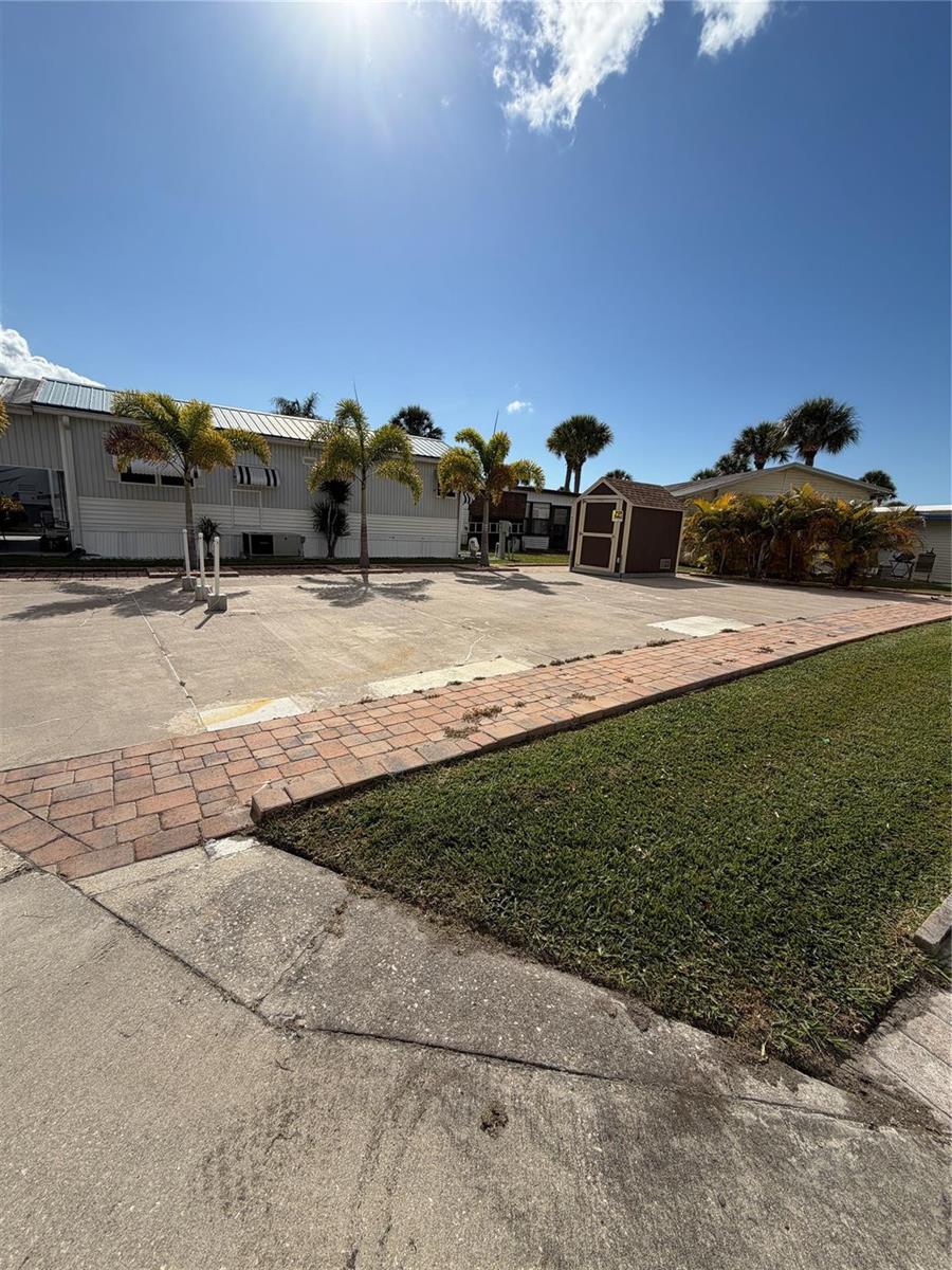 A paved driveway leads to a mobile home with palm trees and a storage shed — 6614 SE 53rd Lane, Okeechobee FL 34974, OKEECHOBEE, FL