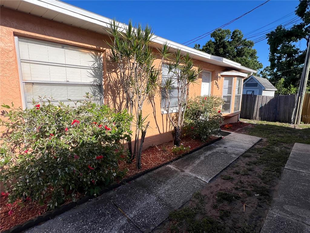 A peach-colored house exterior features a concrete walkway, landscaping, and a bay window — 2983 62ND AVENUE N, ST PETERSBURG, FL