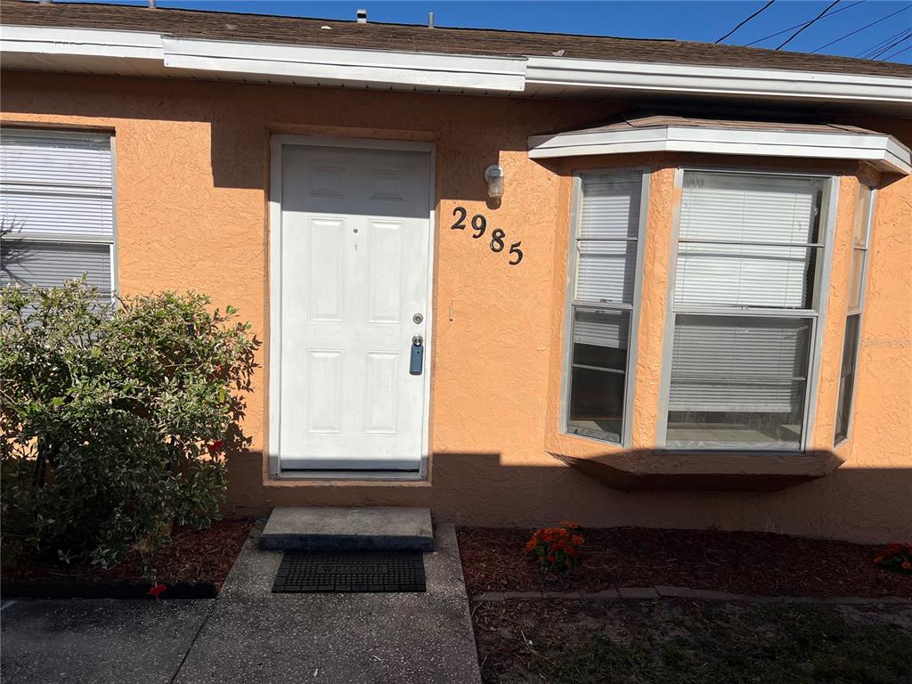 The exterior of a peach-colored house features a white front door and bay window — 2983 62ND AVENUE N, ST PETERSBURG, FL