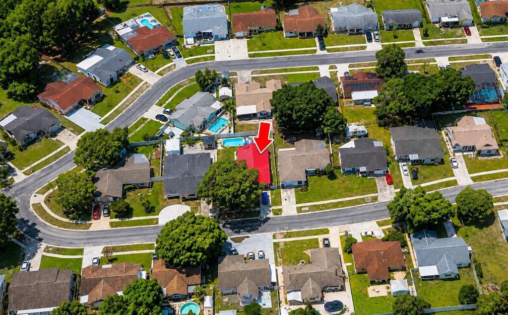 An aerial view shows a residential neighborhood with a house featuring a bright red roof — 6834 GREENWICH AVENUE, NEW PORT RICHEY, FL