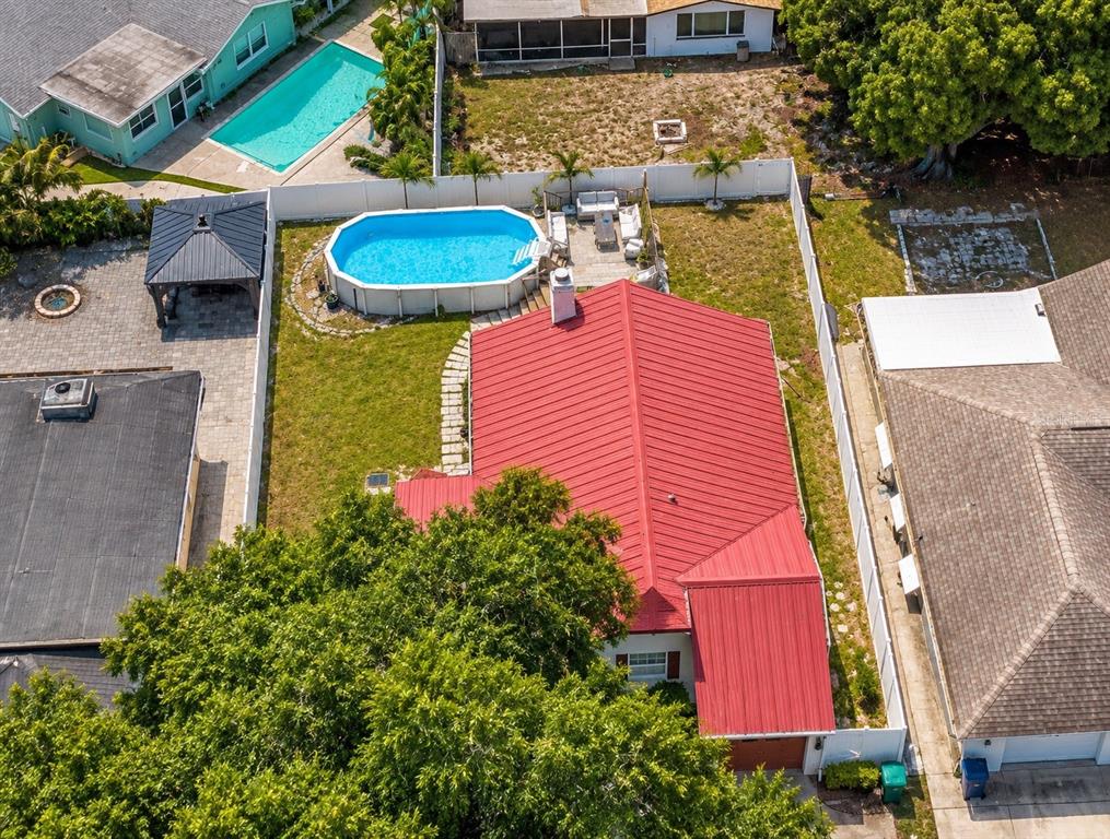 An aerial view shows a house with a red metal roof, a pool, and gazebo — 6834 GREENWICH AVENUE, NEW PORT RICHEY, FL