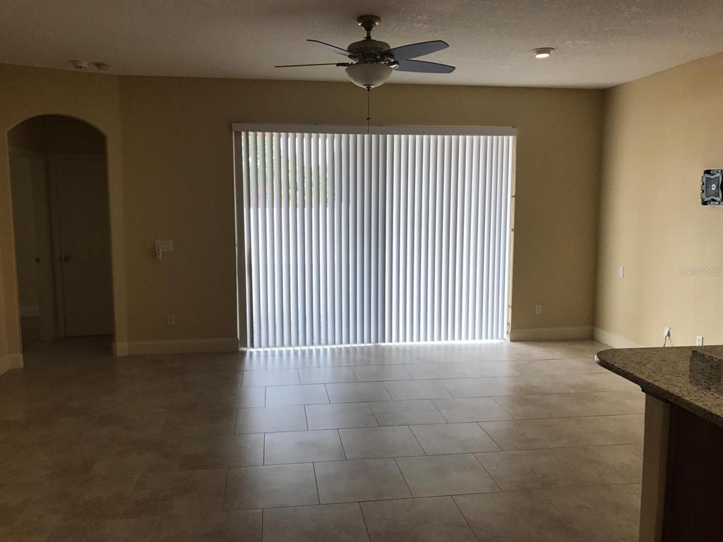 A room with light-colored tile flooring, a ceiling fan, and large sliding glass doors — 6628 BOUGANVILLEA CRESCENT DRIVE, ORLANDO, FL