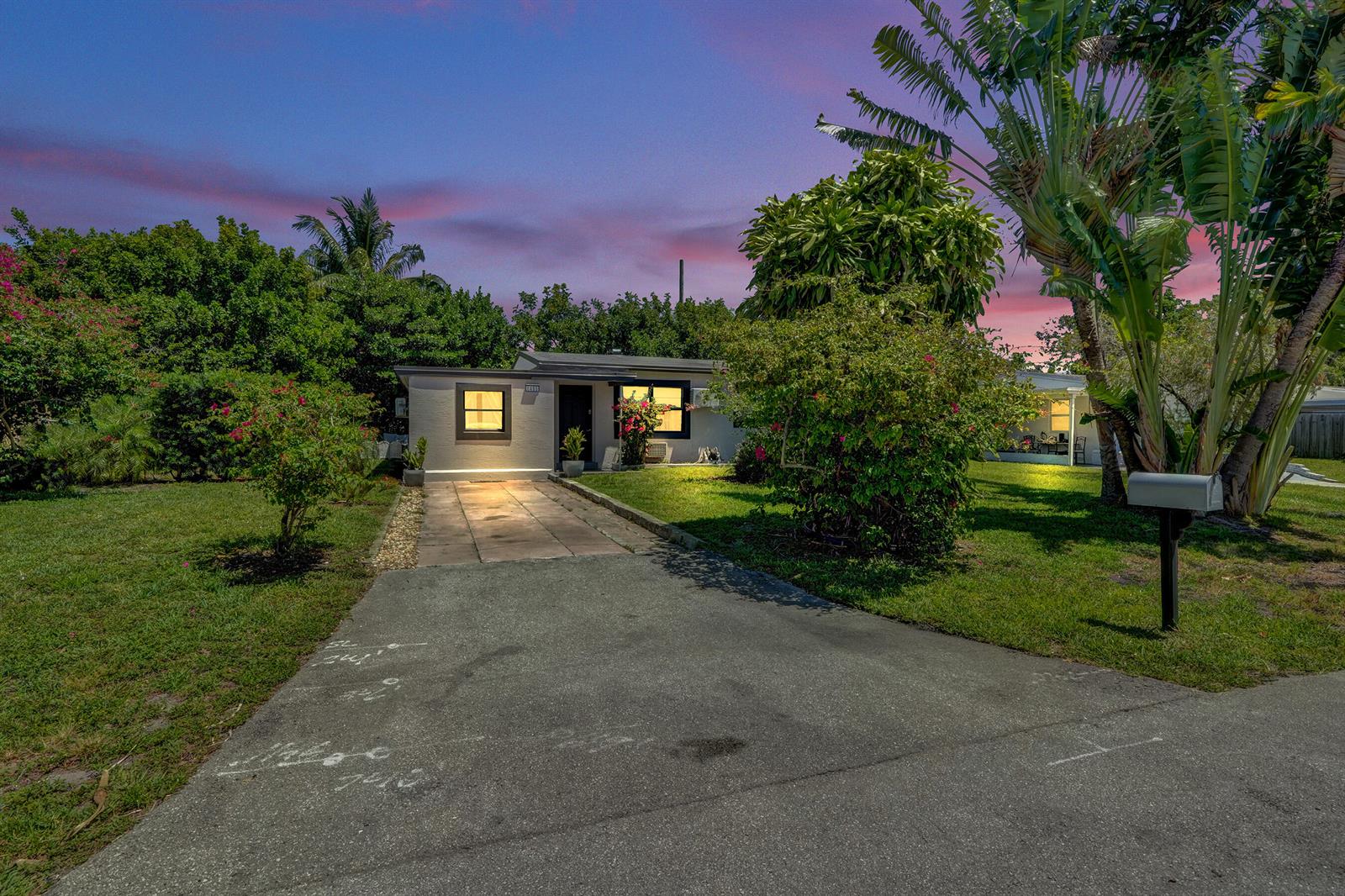 A single-story house with a paved driveway and lush landscaping under a sunset sky — 1465 NE 27th Street, Pompano Beach FL 33064, POMPANO BEACH, FL