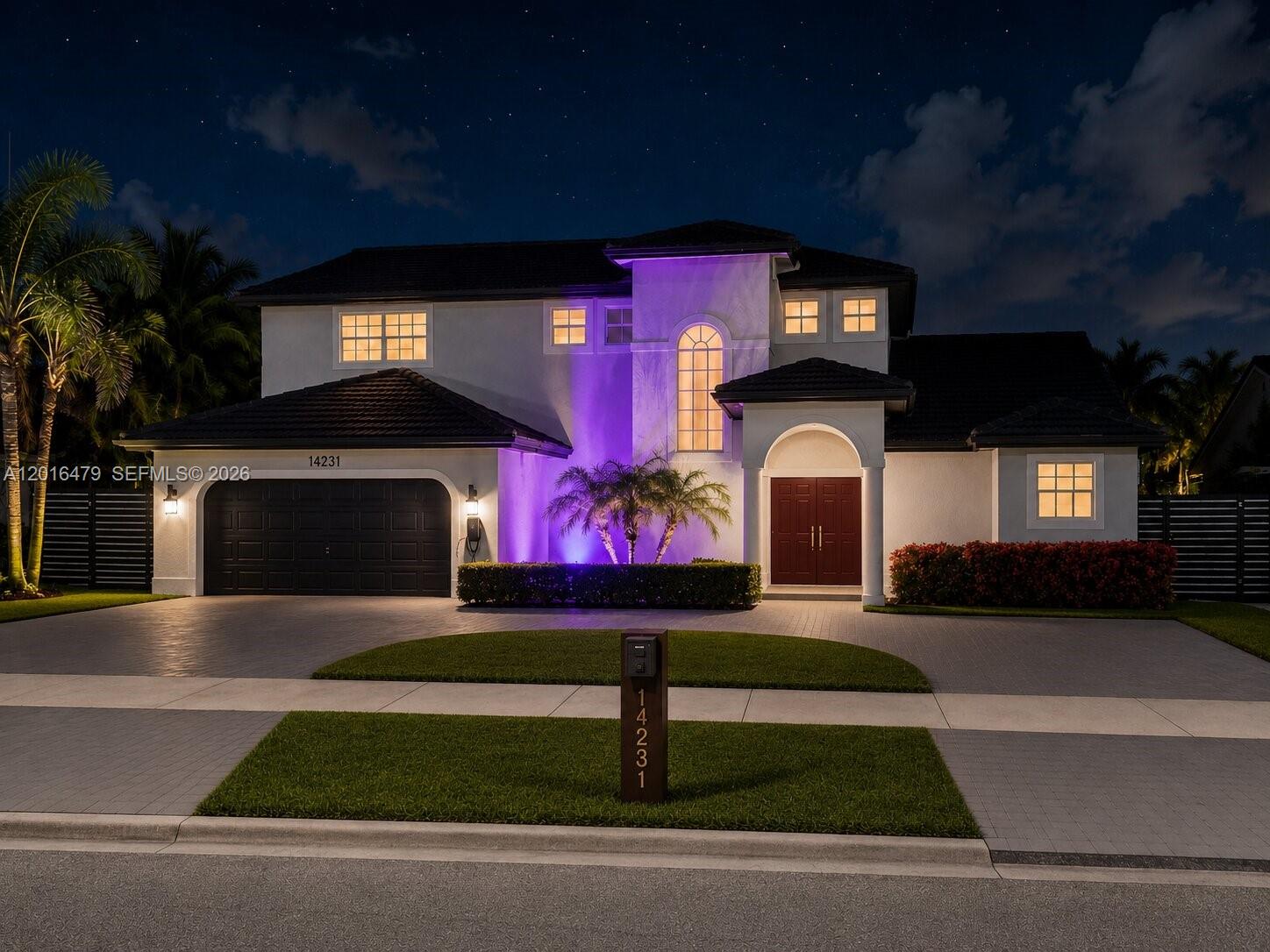 A two-story house with a dark garage, purple accent lighting, and a paved driveway at night — 14231 SW 36th St, Miami FL 33175, MIAMI, FL