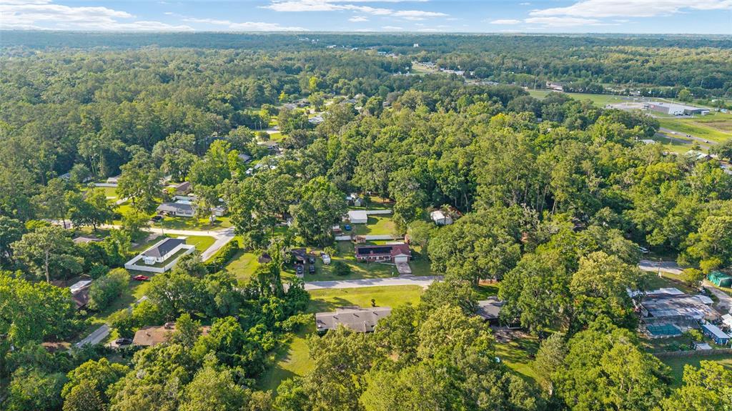 An aerial view shows several houses nestled among dense trees in a suburban neighborhood — 2550 SE 67TH STREET, OCALA, FL