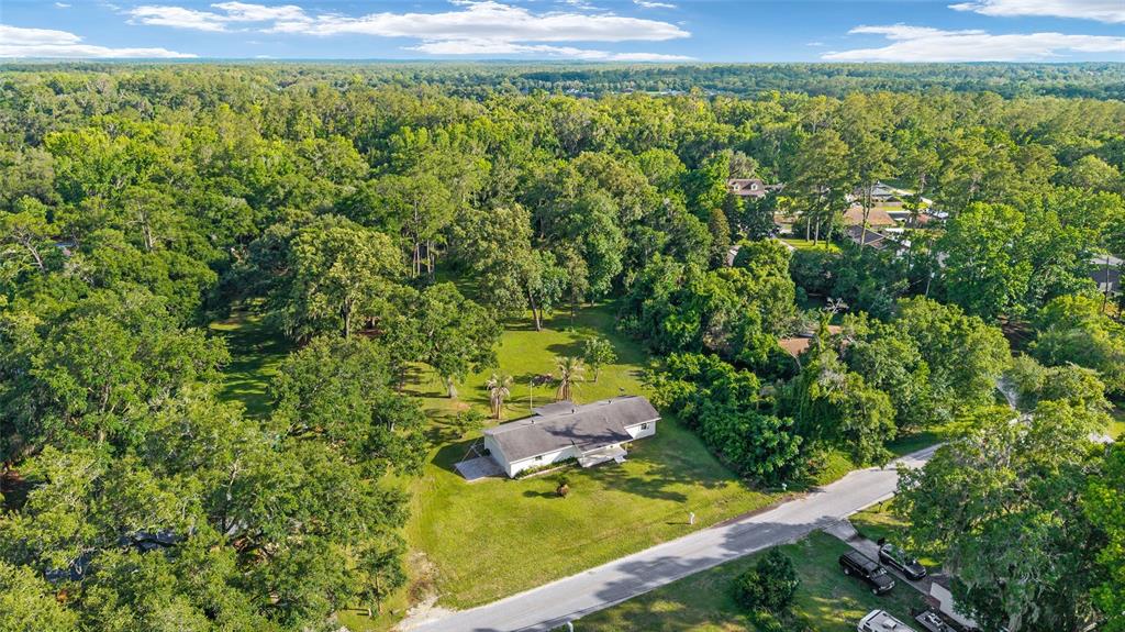 An aerial view shows a single-story house situated on a large, tree-filled grassy lot — 2550 SE 67TH STREET, OCALA, FL